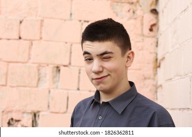 Happy Teenager Boy Wink Close Up Portrait On White Wall Background