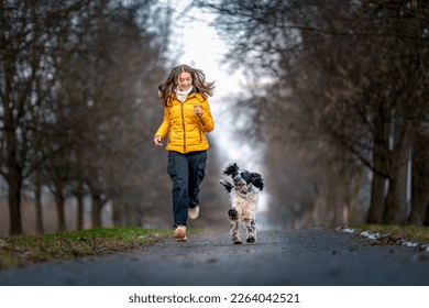 a happy teenager with a dog runs along an alley among the trees. english setter - Powered by Shutterstock