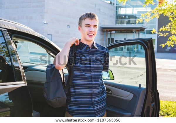 Happy teenager exiting his car\
and putting on his backpack as he arrives at school in the\
morning.