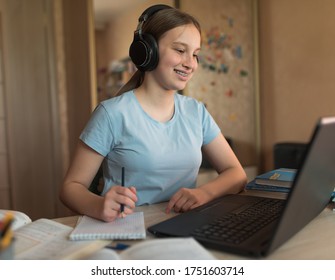 Happy Teenager Girl Smiling On Video Call With Teacher And Parent, Internet Conference, Home Education And Learning To School College. Headphones Notepad And Notebook Writing.