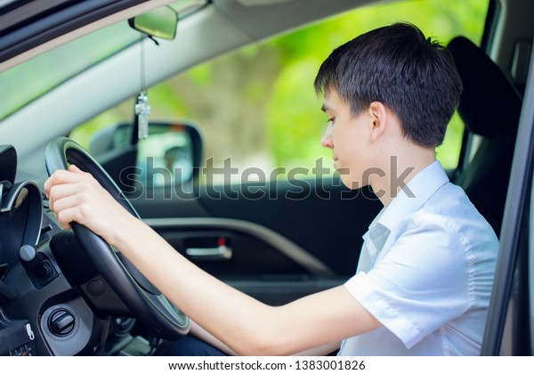 happy teenager got a driver\'s license and sits behind\
the wheel of a car