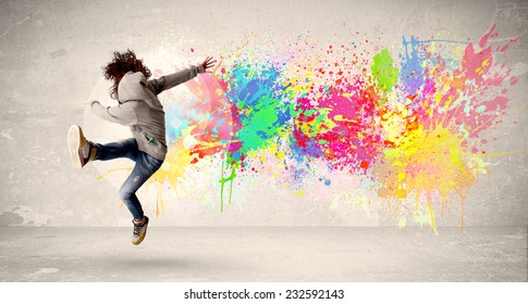 Happy Teenager springt mit buntem Tintenfleck auf städtischem Hintergrund