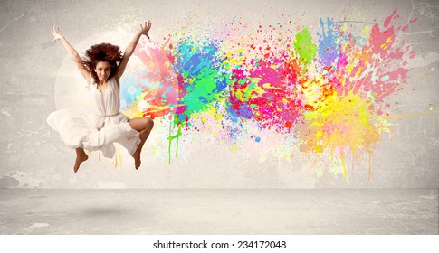 Happy Teenager springt mit buntem Tintenfleck auf städtischem Hintergrund Konzept