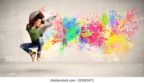 Happy teenager jumping with colorful ink splatter on urban background concept