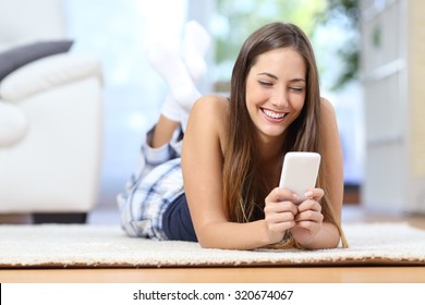 Happy Teenager Texting On The Mobile Phone Lying On A Carpet In The Living Room