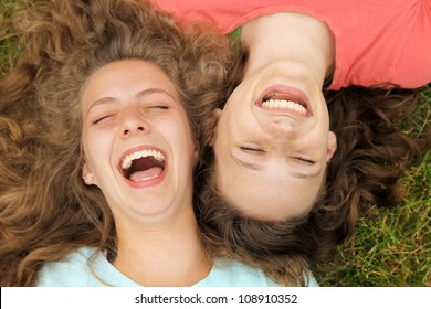 Happy teenagers friends lying on a grass laughing in a park - Powered by Shutterstock