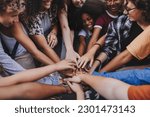 Happy teenagers putting their hands together in a huddle. Group of multicultural young kids stacking hands together in unity