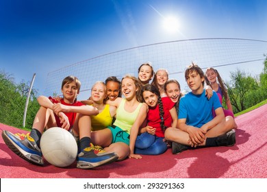 Happy teenagers who sit on volleyball game court
