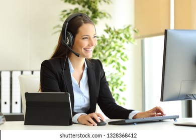 Happy tele marketer working at office with desktop computer and tablet