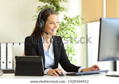 Happy tele marketer working at office with desktop computer and tablet