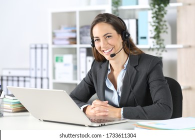 Happy telemarketer woman with headset and laptop posing looking at camera sitting on a desk at the office - Powered by Shutterstock