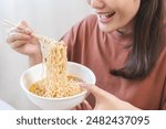 Happy temptation, attractive asian young student woman, cute girl using chopsticks eating instant ramen, noodles soup from a bowl, cooking meal fast food lifestyle of traditional japanese person.