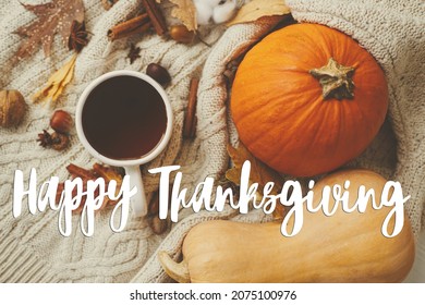 Happy Thanksgiving Card. Happy thanksgiving text on  cup of tea, knitted sweater, pumpkins, autumn leaves, candle, flat lay. Seasons greetings, handwritten lettering. Give thanks