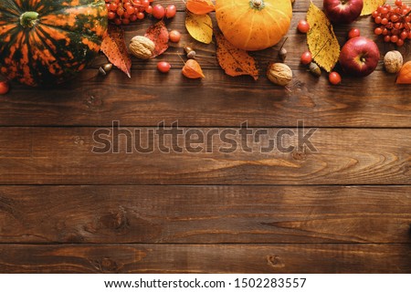 Happy Thanksgiving concept. Autumn composition with ripe orange pumpkins, fallen leaves, dry flowers on rustic wooden table. Flat lay, top view, copy space.