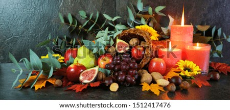 Happy Thanksgiving cornucopia table setting centerpiece decorated with autumn leaves, fruit, nuts and orange burning candles, web banner.