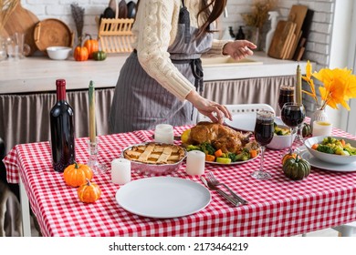 Happy Thanksgiving Day. Autumn Feast. Woman Celebrating Holiday Cooking Traditional Dinner At Kitchen With Turkey, Vegetables And Pumpkin Pie, Cutting Pie