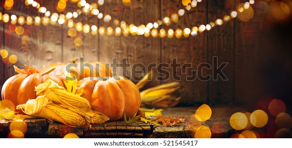 Happy\
Thanksgiving Day background, wooden table decorated with Pumpkins,\
Corncob, Candles and autumn leaves garland. Beautiful Holiday\
Autumn festival concept scene Fall,\
Harvest