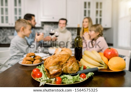 Happy Thanksgiving Day. Family sitting at the table and celebrating holiday. Grandfather, mother, father and children. Traditional turket, fruits and wine on the table. Focus on turkey