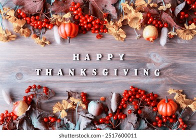 Happy Thanksgiving day holiday autumn background with Happy Thanksgiving letters, seasonal autumn nature berries, pumpkins, apples and flowers on the wooden background