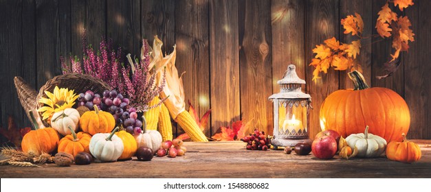 Happy Thanksgiving. Decorative cornucopia with pumpkins, squash, fruits and falling leaves on rustic wooden table - Shutterstock ID 1548880682