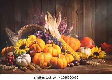 Happy Thanksgiving. Decorative Cornucopia With Pumpkins, Squash, Fruits And Falling Leaves On Rustic Wooden Table