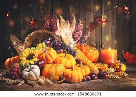 Happy Thanksgiving. Decorative cornucopia with pumpkins, squash, fruits and falling leaves on rustic wooden table