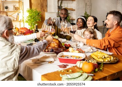 Happy Thanksgiving Dinner Party With Family And Friends With Turkey And Traditional Food, Dishes On Festive Table. Multiethnic, Mixed Ages People Sitting Together Around Table And Celebrate Holiday.