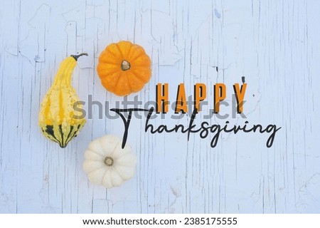 Happy Thanksgiving greeting on rustic white background for holiday card with pumpkins and gourd.