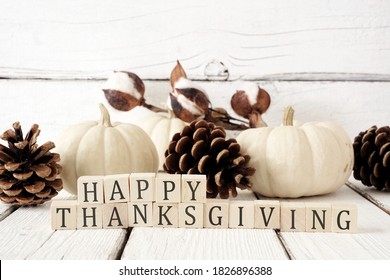 Happy Thanksgiving greeting on wooden blocks against a white wood background with white pumpkins and brown autumn decor