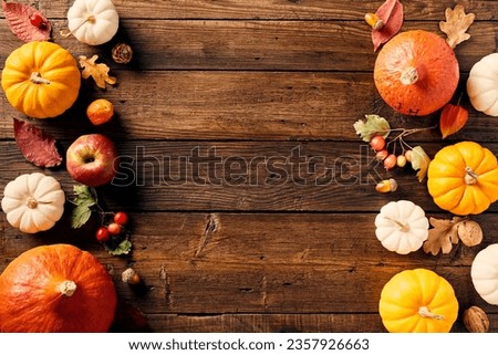 Happy Thanksgiving holiday background. Flat lay, top view pumpkins, apple, red berries, fall leaves, walnuts on wooden desk table.