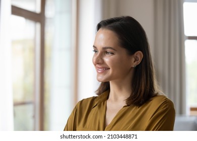 Happy thoughtful millennial business woman in casual looking at window with pensive dreamy smile, thinking of work project future vision, ambitious career, planning goals. Head shot portrait