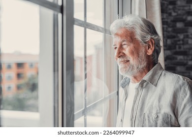 Happy thoughtful older 70s man looking out of window away with hope, thinking of good health, retirement, insurance benefits, dreaming of future. Elderly pensioner waiting meeting with family - Shutterstock ID 2264099947