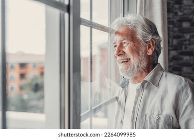 Happy thoughtful older 70s man looking out of window away with hope, thinking of good health, retirement, insurance benefits, dreaming of future. Elderly pensioner waiting meeting with family - Powered by Shutterstock