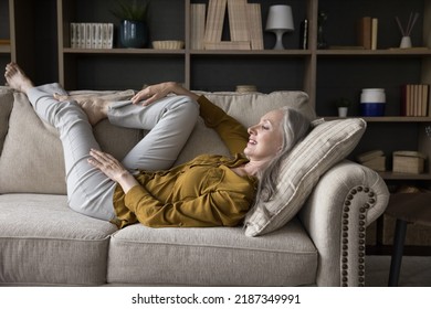 Happy thoughtful relaxed grey haired woman lying on comfortable couch, leaning legs on back, looking at window away, thinking, dreaming, smiling. Home leisure, recovery concept - Powered by Shutterstock