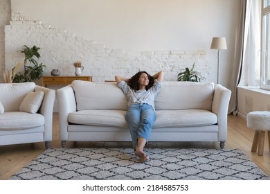 Happy thoughtful young Latin woman resting on comfortable couch at home, looking away, smiling, dreaming, thinking, relaxing, enjoying leisure time, breathing fresh air - Shutterstock ID 2184585753