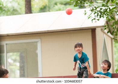 Happy Three Cute Asian Kids Playing Basketball In The Park With Sun Light Background. Funny Adorable Asia Brother And Two Sister Playing Mini Ball In The Garden. Selective Focus