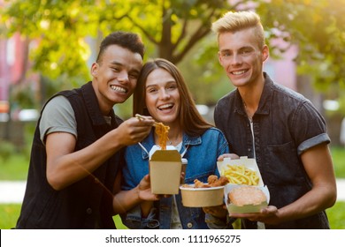 Happy Three Friends. College Mates Are Hanging Out Together And Eating Yummy Noodles, Nuggets, Potato Frites And Burgers.