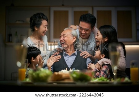 happy three generation asian family celebrating grandpa's birthday at home