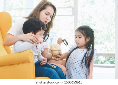 Happy Time Of Family. Mom Teaching Her Son And Daugther To Used Magnifying Glass Looking On Globe At Home. Learning And Discovery Convept.