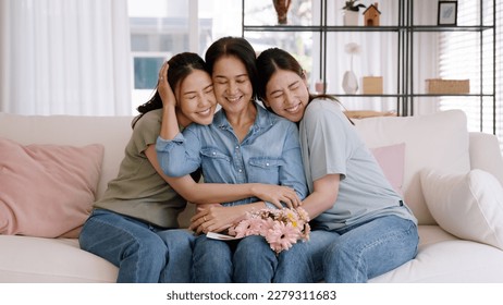 Happy time May Mother day cuddle hug care love face to face kiss cheek to mature mum. Asia middle aged old mom adult people smile enjoy receive gift flower from young child sitting at home sofa relax. - Powered by Shutterstock