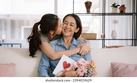 Happy time Mother day grown up child looking at camera cuddle hug give flower gift box red heart card to mature mum. Love kiss care mom asia middle age adult people smile enjoy sitting at home sofa. - Powered by Shutterstock