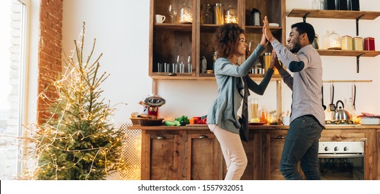 Happy time together. Cheerful african-american couple laughing in kitchen at Christmas morning, panorama, copy space - Shutterstock ID 1557932051