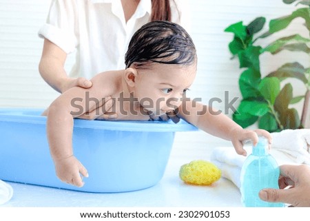 Happy toddle baby infant has fun while taking bubble bath in bathroom, mother bathing kid in tub, mom washing and cleaning her little toddler girl daughter child in bath, childhood and parent care.