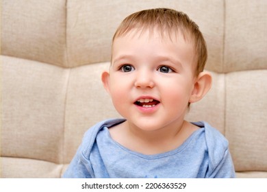 Happy Toddler Baby Boy, Sofa Background In Home Living Room. Portrait Of A Cute Smiling Child, Close-up. Kid Aged One Year And Two Months