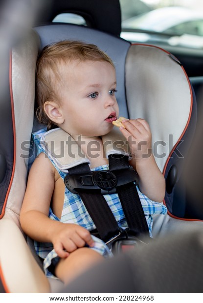 Happy Toddler boy\
in the car eating cookies