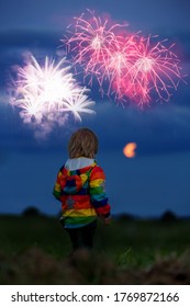 Happy Toddler Boy, Child, Looking At Fireworks For 4th Of July In A Field, Full Moon Rising Up In The Sky