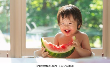 Happy Toddler Boy Eating Watermelon In His Highchair