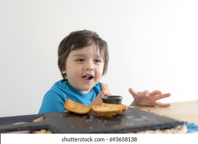 Happy Toddler Boy Enjoy Eating Baked Fried Potatoes On Black Slate Plate With Tomato Sauce, Home Made Chips Wedges Country Style For Kid Snack At Home