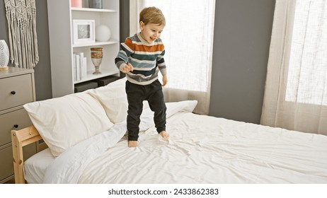 Happy toddler boy in striped sweater jumps on a clean bed in a cozy bedroom interior. - Powered by Shutterstock