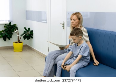 Happy toddler boy with a woman mother in the clinic waiting for a doctor s appointment. Mom with a baby boy in a modern hospital before receiving a pediatrician. Kid 5-6 year old - Powered by Shutterstock